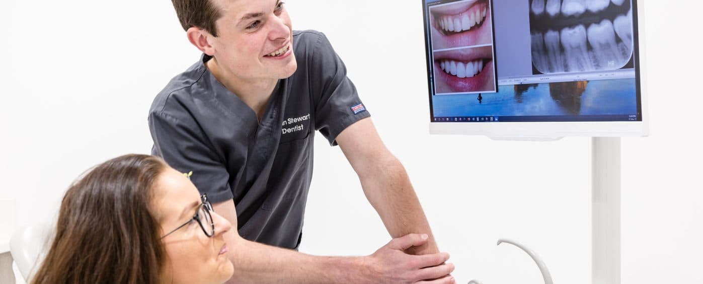 A dentist showing a patient their treatment plan on screen